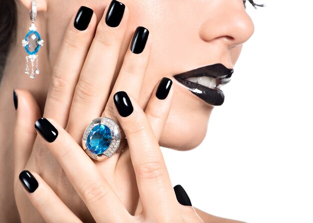 Closeup face of young beautiful woman with black manicure and fashion bright makeup