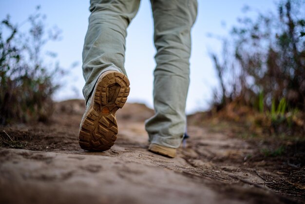 緑の森を歩いて旅行するためにブーツを履いているクローズアップの足ハイカー男旅行休暇とハイキングのコンセプト