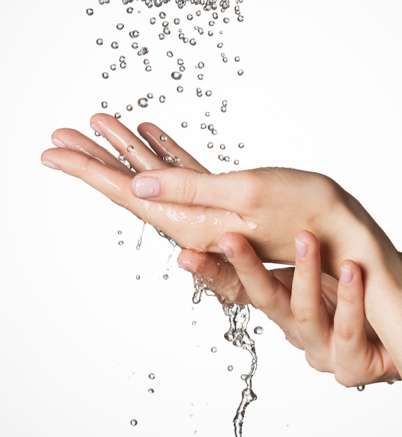 Free photo closeup female hands under the falling drops of  water - skin care concept