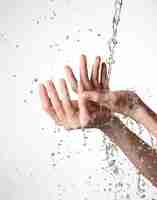 Free photo closeup female hands under the stream of splashing water - skin care concept