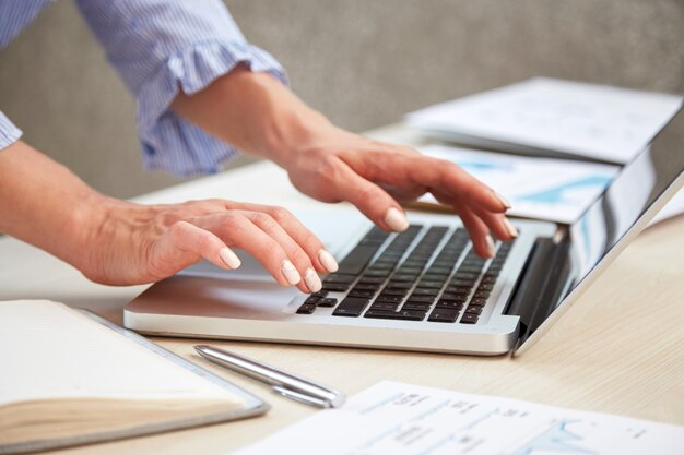 Closeup of female hands typing on laptop keyboard