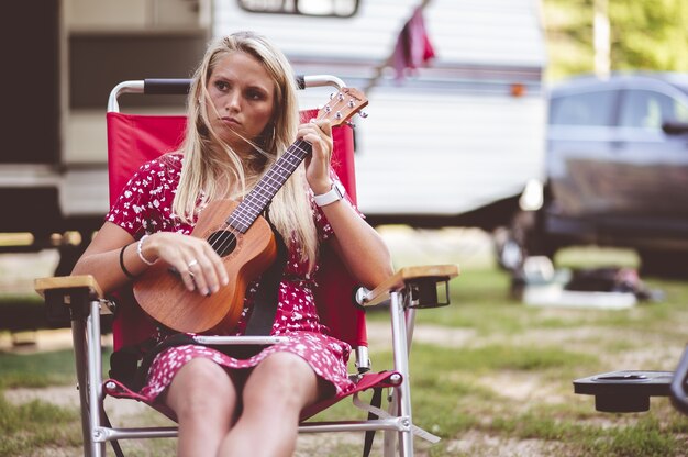 Closeup focus portrait of a beautiful young woman holding a ukulele