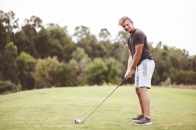 ゴルフをしている若い男のクローズアップフォーカスの肖像画