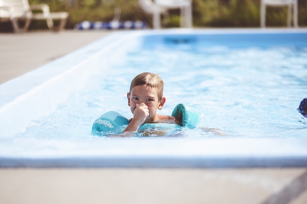 Closeup focus shot of a cute young boy swimming in the pool