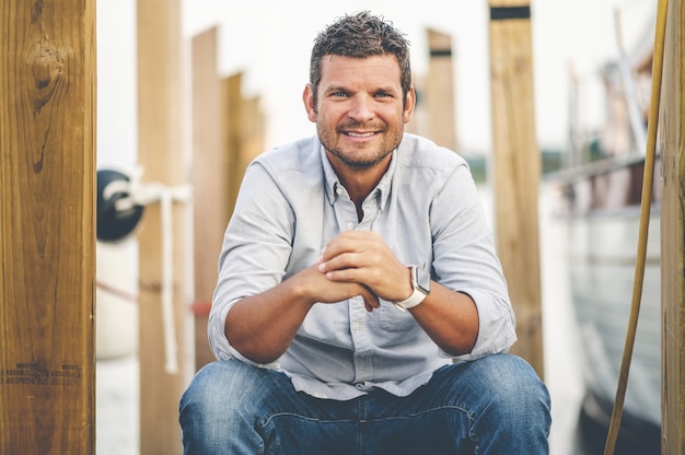 Free photo closeup focus shot of a handsome adult man sitting at a pier