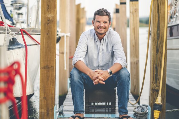 Closeup focus shot of a handsome adult man sitting at a pier