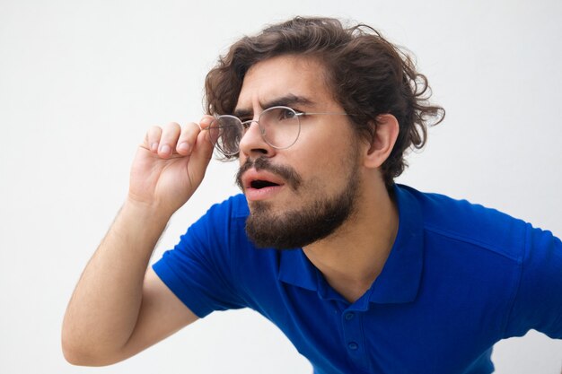 Closeup of focused attentive guy in glasses staring away