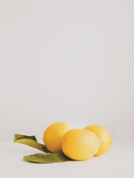 Closeup of fresh ripe yellow lemons with leaves on a white