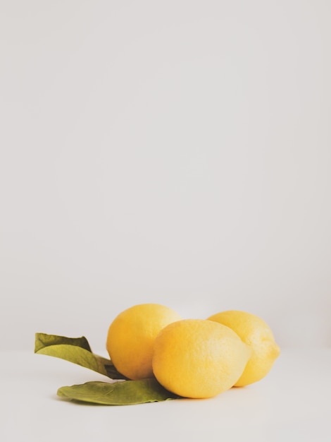 Closeup of fresh ripe yellow lemons with leaves on a white