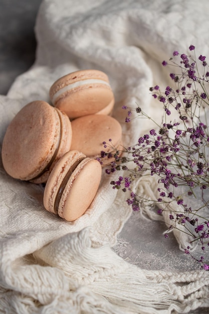 Closeup of the fresh sweet macaroons on the white fabric with decorative flowers