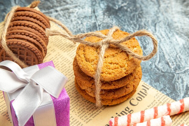 Closeup front view cookies tied with ropes xmas ornaments on newspaper on grey background