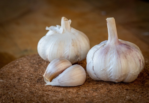 Closeup of garlic bulb and cloves on a round cork board