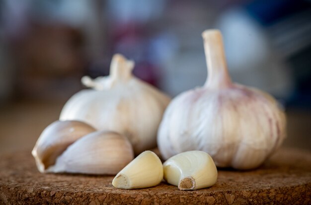 Closeup of garlic bulb and cloves on a round cork board