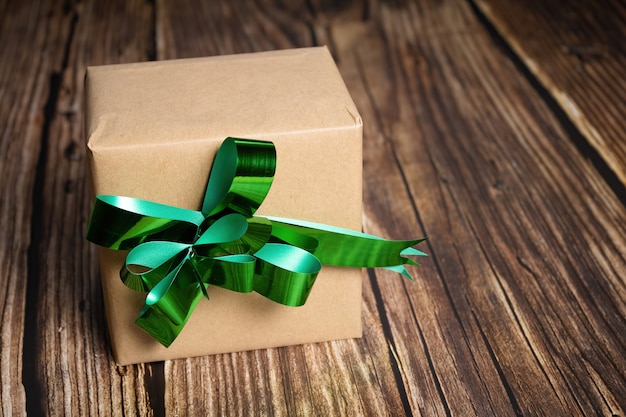 Closeup of a gift box with a green ribbon on wooden background