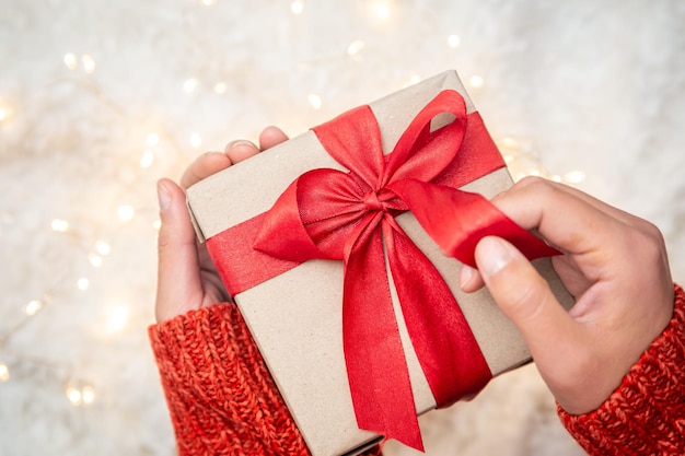 Free photo closeup gift box with red ribbons in female hands top view