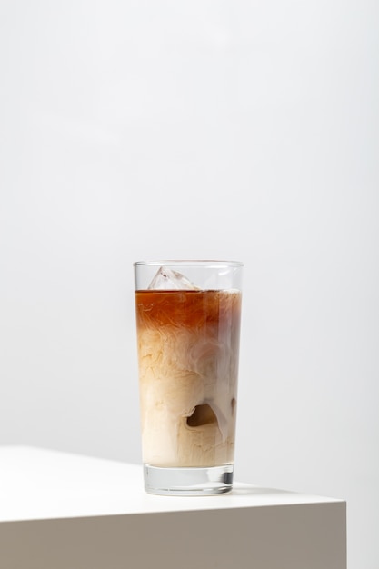 Closeup of a glass of ice tea with milk on the table on white