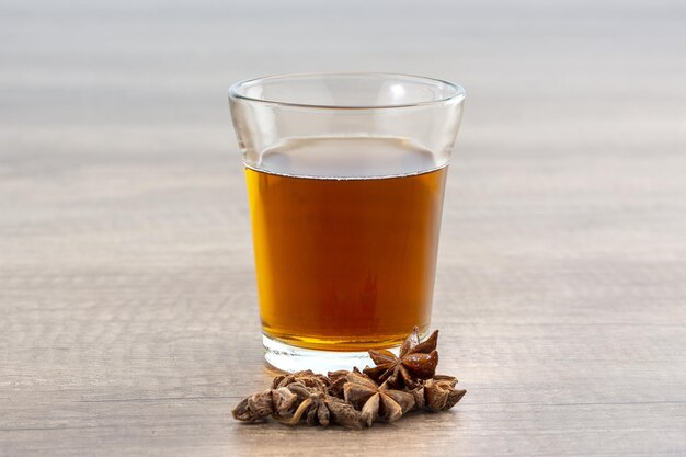 Closeup of a glass of tea with star anise on a wooden surface with a blurry background