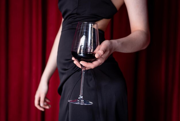 이브닝 드레스를 입은 여성의 손에 있는 와인 한 잔