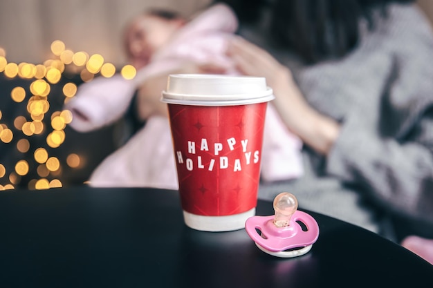 Closeup of a glass with the inscription happy holidays and a baby pacifier