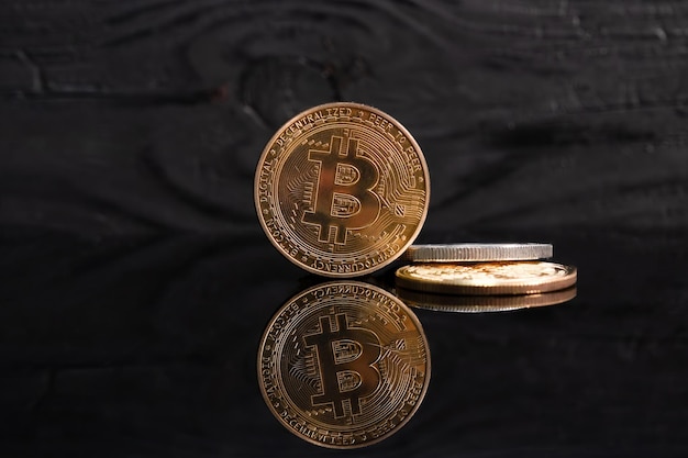 Closeup of a golden bitcoin on a dark reflective surface and the histogram of decreasing crypto