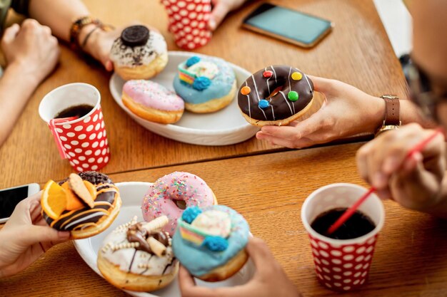 Closeup of group of friends eating donuts for dessert in a cafe