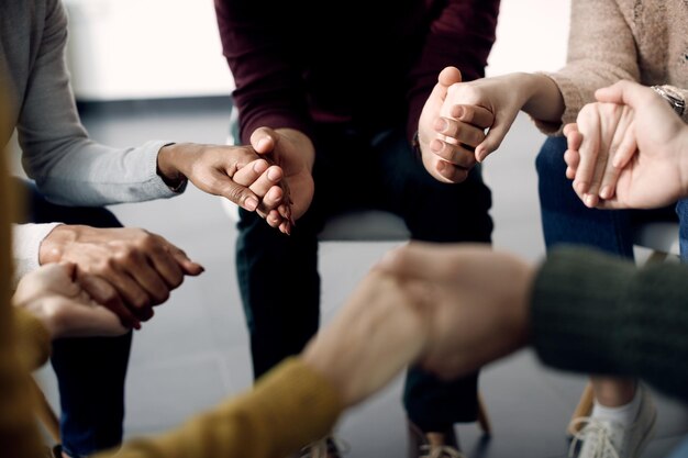 心理療法のセッション中に手を握っている人々のグループのクローズアップ