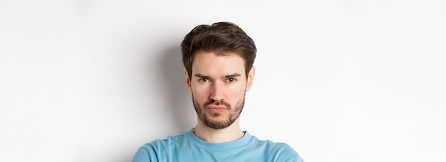 Free photo closeup of grumpy young man grimacing sulking and making offended face standing upset over white bac