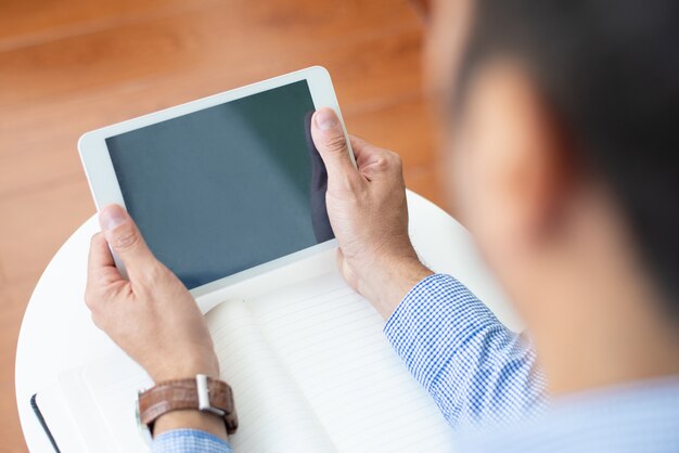 Closeup of guy using tablet computer at coffee table