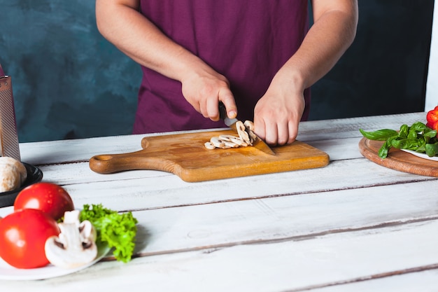 Foto gratuita mano del primo piano del panettiere del cuoco unico che produce pizza alla cucina