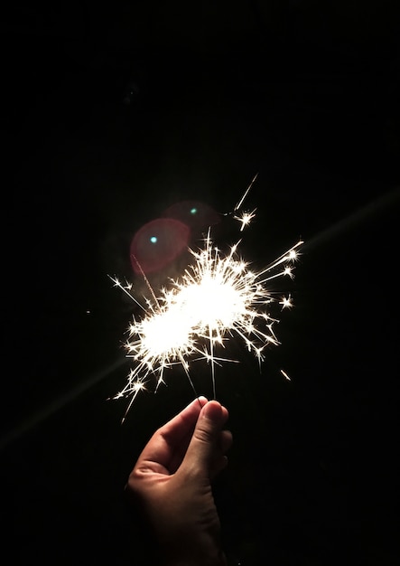 黒の背景とsparklerを保持する手の拡大