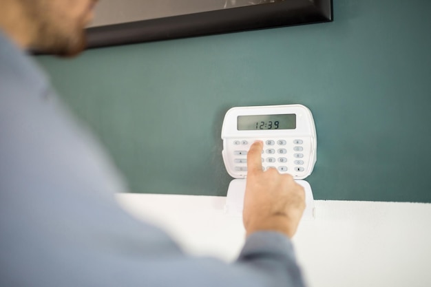 Closeup of the hand of a man using a keypad to arm his home alarm system