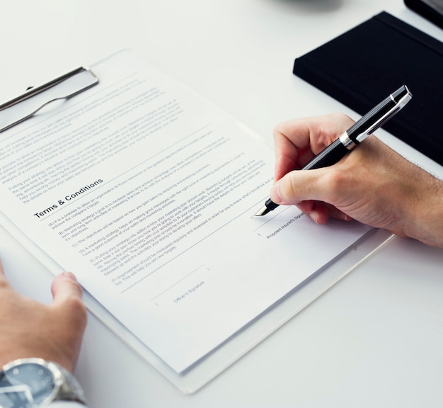 Closeup of hand signing paper workspace