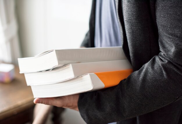 Closeup of hands holding stack of books