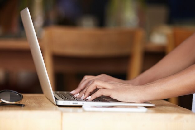 Closeup of hands typing on laptop keyboard