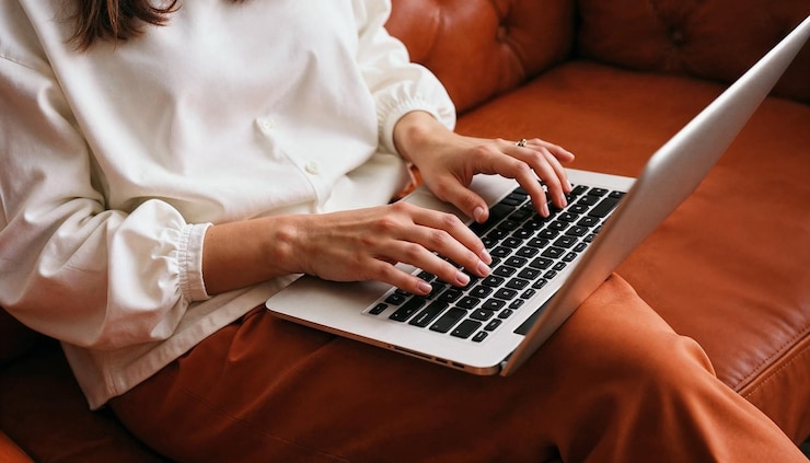 Free Photo closeup of hands typing on a laptop on a leather sofa