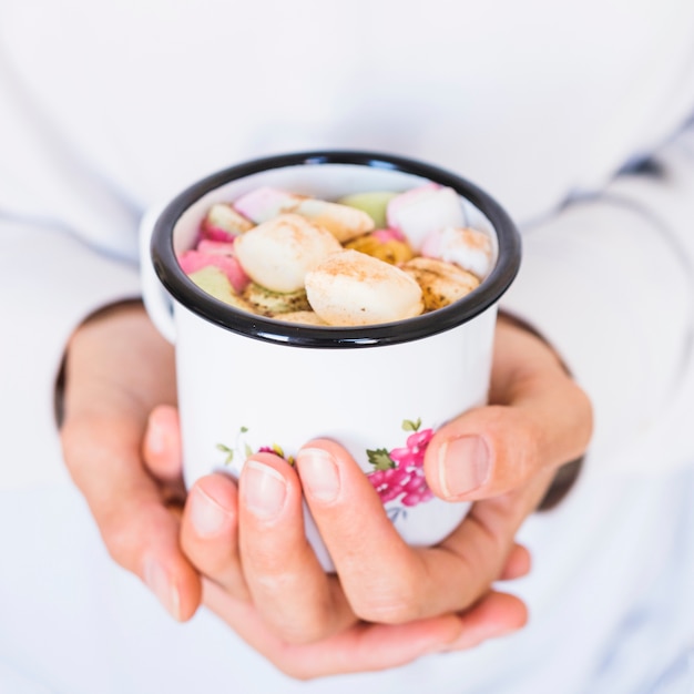 Foto gratuita mani del primo piano con la tazza di bevande e marshmallow