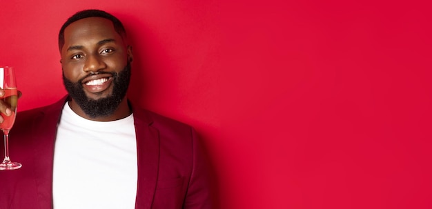 Free photo closeup of handsome smiling black man saying toast raising glass of champagne for merry christmas an