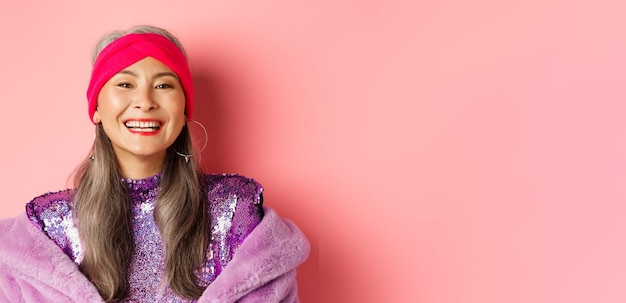 Free photo closeup of happy asian senior lady in trendy purple outfit laughing and smiling at camera having fun