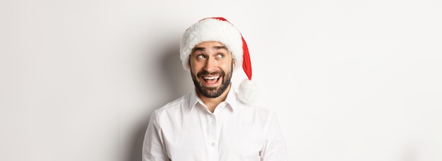 Free photo closeup of happy bearded man in santa hat celebrating christmas and new year and looking at upper le