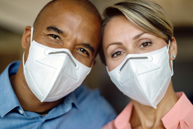 Closeup of happy multiethnic couple with protective face masks looking at camera