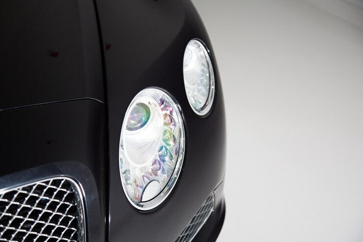 Free Photo closeup of the headlight of a black luxury car under the lights against a grey background