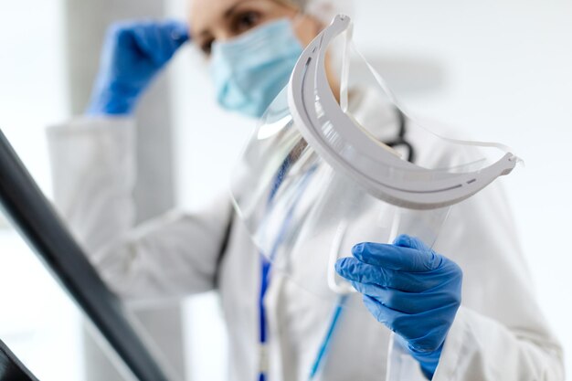 Closeup of healthcare worker holding visor at medical clinic