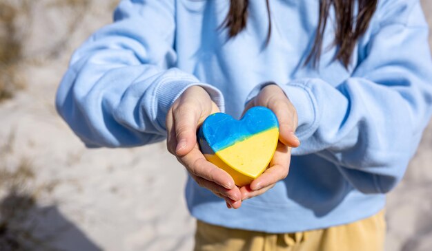 Closeup heart in the color of the flag of ukraine in female hands