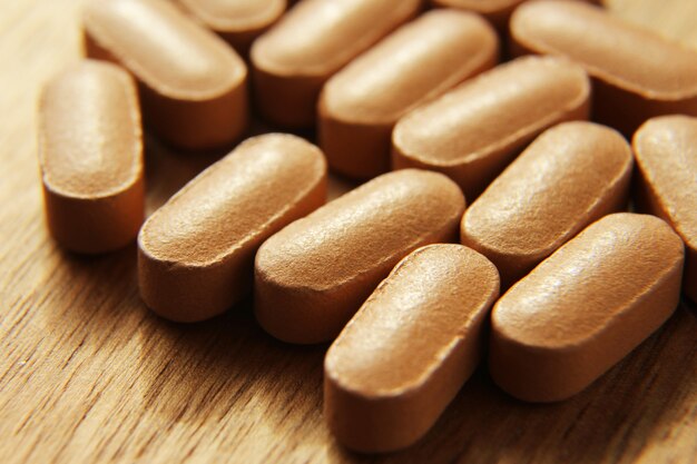 Closeup high angle shot of bunch of pills on a wooden surface