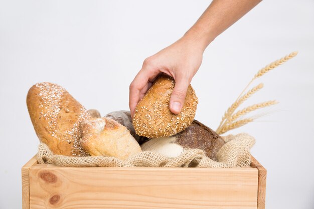 Крупным планом человеческой руки, положить хлеб в деревенский деревянный ящик