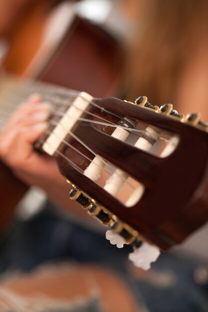 Макрофотография изображение гитары в руках женщины
