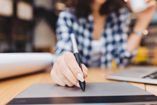 Closeup image hand of woman designing on table in library surround work stuff. Laptop, creative work, graphic design, freelancer, smart student, love job.