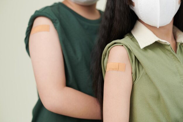 予防接種を受けた子供の肩に絆創膏のクローズアップ画像