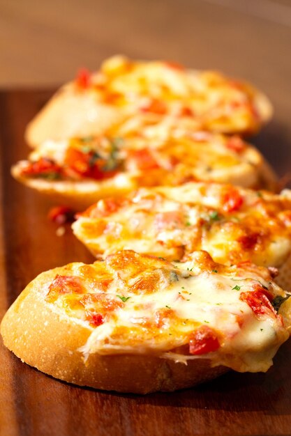 나무 테이블 h에 토마토 소스와 파마산 치즈를 곁들인 이탈리아 전채 브루스케타를 클로즈업