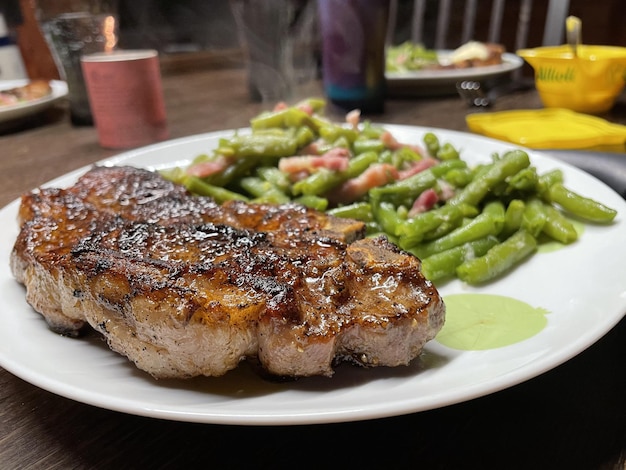 白いプレートにサヤインゲンのサラダとジューシーな肉のクローズアップ